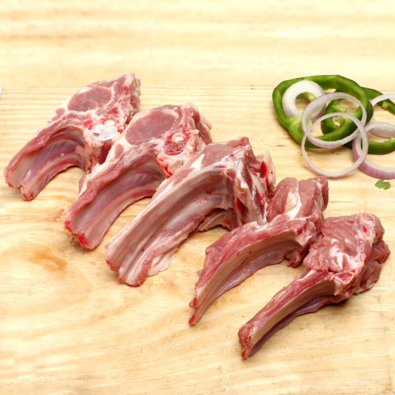 Mutton chaap 1 kg arranged on a wooden cutting board with sliced green bell peppers and red onions, set against a light-colored background. Smart Chicken
