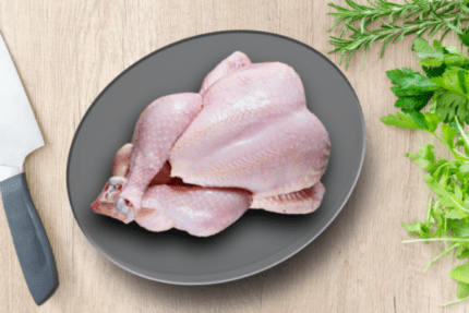 Chicken skin whole 1 kg on a dark plate on wood, with a knife to the left and fresh rosemary and parsley to the right. Smart Chicken