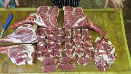 A person in a striped apron stands behind a table displaying a butcher block with Fresh Mutton, including whole pieces, chops, and leg cuts weighing 1 kg, alongside a knife. Smart Chicken